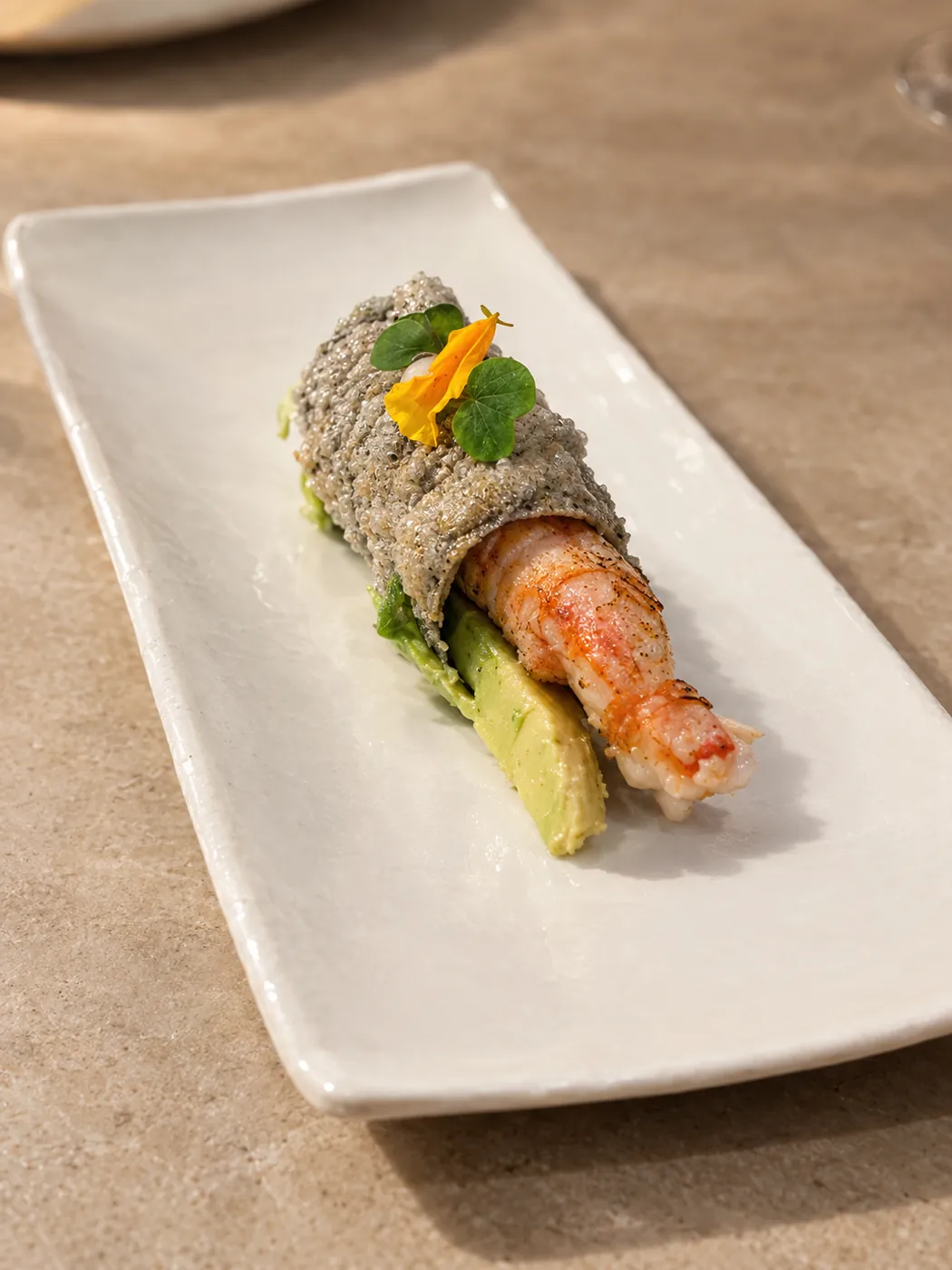 Plato minimalista de langostino sobre aguacate